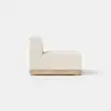 A modern armless beige upholstered chair with a wooden base, shown from the side against a plain white background.