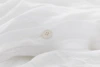 A close-up of a soft, white fabric with subtle folds and gentle shadowing, suggesting a lightweight and smooth texture.