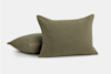 Two olive green, square, textured throw pillows with subtle tufted details, one standing upright and the other lying flat on a plain white background.