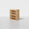 A wooden shelving unit with three open shelves and a flat top, placed on a smooth, light gray floor against a plain white background.