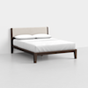 A modern wooden bed frame with a beige upholstered headboard, dressed with white bedding and two white pillows, placed in a minimal, light gray room.