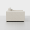 A side view of a modern beige upholstered sofa with two back cushions, set against a plain light gray background.