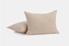 Two beige, textured pillows lie on a white background; one pillow is upright while the other rests flat behind it.