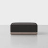 A modern, rectangular black ottoman with a light wood base, shown against a plain light gray background.