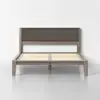 A modern wooden bed frame with a dark upholstered headboard, exposed wooden slats, and clean, minimalist lines, set against a plain white wall and a light gray floor.