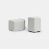 Two light gray, rectangular fabric ottomans with black bases are placed on a plain white background. One ottoman is positioned horizontally, while the other stands vertically.
