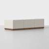 A modern, minimalist beige sectional sofa with three seat sections and a low wooden base, set against a plain light gray background. The sofa has clean lines and no visible cushions or armrests.