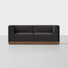 A modern, dark gray two-seater sofa with wooden base, set against a plain white background. The design is boxy and minimalist, with clean lines and simple geometric shapes.