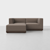 A modern, L-shaped sectional sofa with brown fabric upholstery and a dark wooden base sits on a light gray floor against a plain white background.