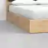 Close-up of a light wood bed frame with a white mattress and pillows, set on a smooth, light gray floor in a minimalistic room.