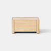 A small, rectangular wooden box with short legs and smooth edges, placed on a light gray surface against a plain white background.