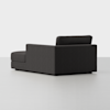 A modern dark gray sectional sofa with clean lines is positioned in a minimalist, light gray room. The sofa is viewed from the back and side, showing one armrest and a backrest.