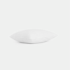 A single white pillow resting on a flat, white surface with a plain white background.
