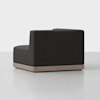 A modern, dark gray upholstered corner sofa with a low wooden base, set against a plain light background. The sofa has clean lines and a minimalist design.