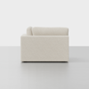 A modern, off-white upholstered sofa viewed from the side, placed on a smooth, light grey floor with a plain white background.