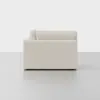 A modern, off-white upholstered sofa viewed from the side, placed on a smooth, light grey floor with a plain white background.