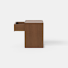 A simple, rectangular wooden pedestal with a smooth finish, placed on a light gray floor against a plain white background.