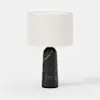 A modern table lamp with a black marble base and a large, cylindrical white fabric lampshade, set against a plain white background.