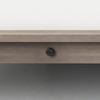 A close-up of a light wood bed frame with a round black screw or cap in the center, set against a light-colored wall and gray floor.
