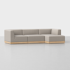 A modern L-shaped sectional sofa with light beige upholstery and a wooden base, placed on a light gray floor against a plain white background.