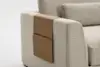 A close-up of a beige upholstered sofa with a tan leather armrest organizer draped over the arm, featuring a pocket for holding items.