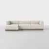 A modern L-shaped sectional sofa with light beige upholstery and a wooden base, placed on a smooth, light gray floor against a plain white background.