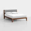 A modern wooden bed frame with a gray upholstered headboard, made up with white sheets, pillows, and a comforter, set against a plain white background.