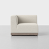 A modern, light beige upholstered corner sofa seat with a wooden base, pictured against a plain, light gray background. The design is minimalist and contemporary.