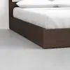 A close-up of a modern bed with a dark wooden frame and white bedding, positioned on a smooth, light gray floor against a plain white wall.