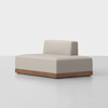 A modern, minimalist armless sofa with a light beige upholstered seat and backrest, set on a rectangular wooden base, against a plain white background.
