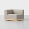 A modern, light gray upholstered corner chair with a square wooden base, placed on a smooth, light-colored floor against a plain white background.