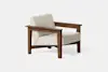 A modern armchair with a light beige upholstered seat and backrest, featuring a sturdy wooden frame and wide, flat armrests, set against a plain white background.