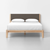 A modern wooden bed frame with a dark gray upholstered headboard, neatly made with white bedding and two white pillows, set against a plain white background.