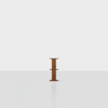 A single small wooden shelf unit with two shelves stands centered in a large, empty, white room with a minimalistic background.