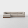 A modern beige sectional sofa with clean lines and a low wooden base, set on a light gray floor against a plain white background.