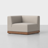A modern, light gray upholstered corner chair with a wooden base sits on a smooth, light-colored floor against a plain white background.