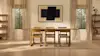 A minimalist dining room with a wooden table and six chairs, neutral curtains, bookshelves on each side, a large abstract painting on the wall, and soft natural light coming through two tall windows.