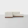 A modern, minimalist sectional sofa with cream-colored upholstery and a wooden base is positioned against a plain white background.
