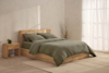 A neatly folded olive green comforter with two matching pillows stacked on top, set against a plain white background.