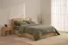 A neatly folded olive green comforter with two matching pillows stacked on top, set against a plain white background.