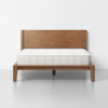 A wooden bed frame with a simple, rectangular headboard and a white mattress. The frame has clean lines and sturdy legs, and the word THUMA is embossed on the side of the mattress. The background is plain and white.