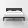 A modern bed with a dark wooden frame, a gray upholstered headboard, and white bedding with two white pillows, set against a plain white background.