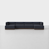 A modern, dark navy blue sectional sofa with low backs and clean lines, set on a wooden base, positioned against a plain white wall on a light gray floor.