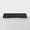 A modern, dark navy blue sectional sofa with low backs and clean lines, set on a wooden base, positioned against a plain white wall on a light gray floor.