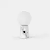 A modern table lamp with a round white frosted glass shade on top of a cylindrical white marble base featuring gray veining and a small black circular button on the front.