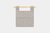 A minimalist gray felt wall organizer with two pockets hangs from a light wooden rod against a plain white background.