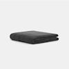 A neatly folded, dark gray weighted blanket is placed on a plain light gray background.