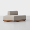 A modern, armless beige sofa with a low backrest and a wooden base, set against a plain white background.