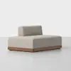 A modern, armless beige sofa with a low backrest and a wooden base, set against a plain white background.