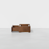 A modern wooden storage box with two compartments, one of which is slid open, sits on a plain light gray floor against a white background.